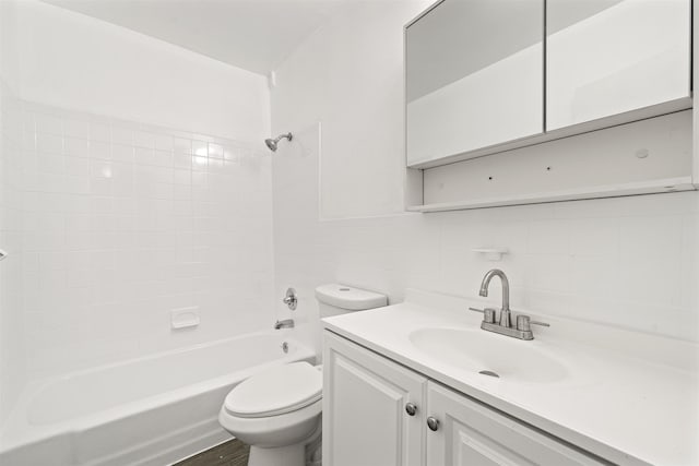 bathroom with toilet, bathing tub / shower combination, vanity, tile walls, and backsplash