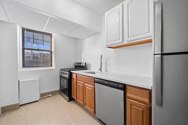 kitchen with light tile patterned floors, white cabinets, appliances with stainless steel finishes, brown cabinets, and a sink