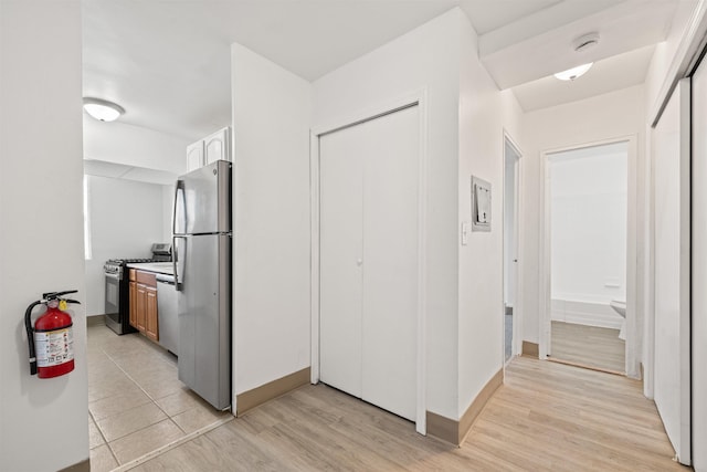 kitchen featuring appliances with stainless steel finishes, light wood-type flooring, light countertops, and baseboards