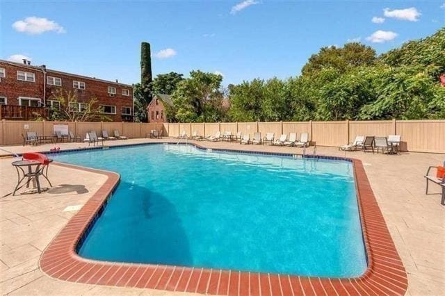 community pool with a patio area and fence