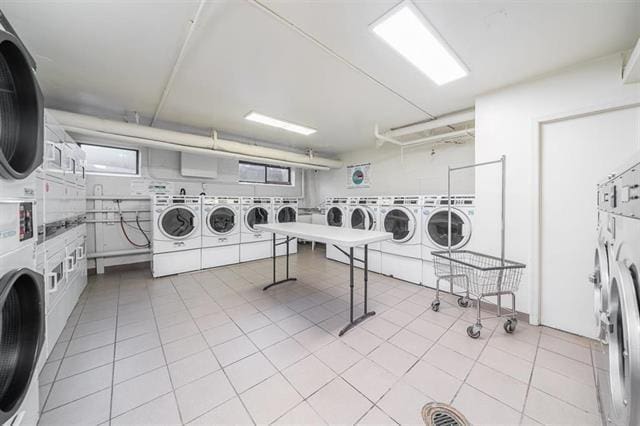 shared laundry area featuring light tile patterned floors, stacked washer and clothes dryer, and washer and dryer