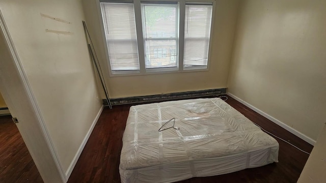 unfurnished bedroom with dark wood-type flooring and baseboard heating