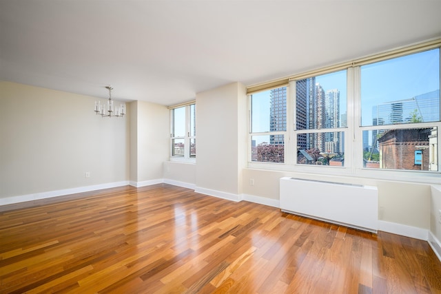 88 Morgan St Unit 802, Jersey City, NJ 07302 - unfurnished room featuring radiator, a chandelier, wood finished floors, and plenty of natural light