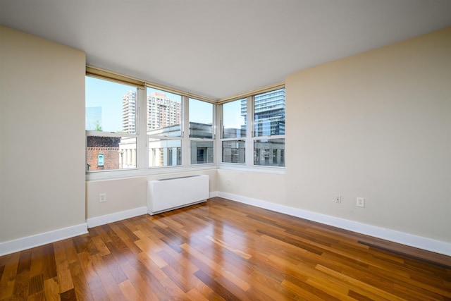 88 Morgan St Unit 802, Jersey City, NJ 07302 - spare room with radiator, a city view, wood finished floors, and plenty of natural light