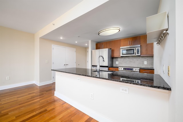88 Morgan St Unit 802, Jersey City, NJ 07302 - kitchen with stainless steel appliances, brown cabinets, decorative backsplash, wood finished floors, and recessed lighting