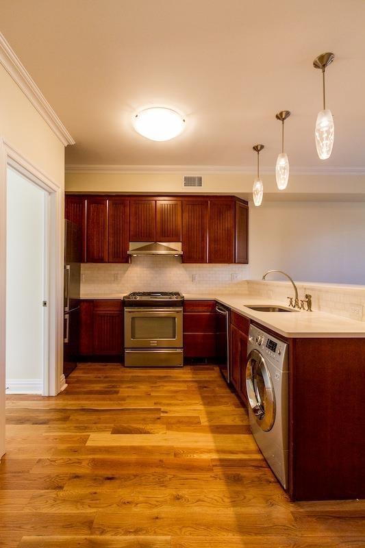 385 1st St, Jersey City, NJ 07302 - kitchen with appliances with stainless steel finishes, washer / dryer, a sink, under cabinet range hood, and ornamental molding
