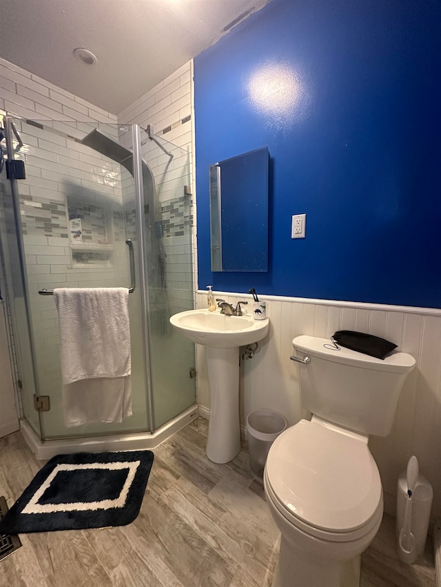 bathroom with walk in shower, sink, toilet, and hardwood / wood-style floors