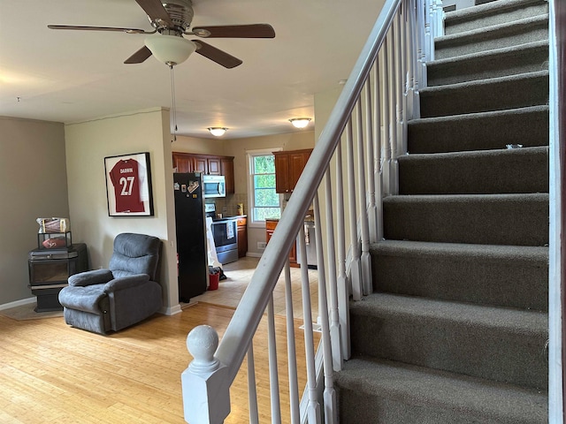 stairs featuring hardwood / wood-style flooring and ceiling fan