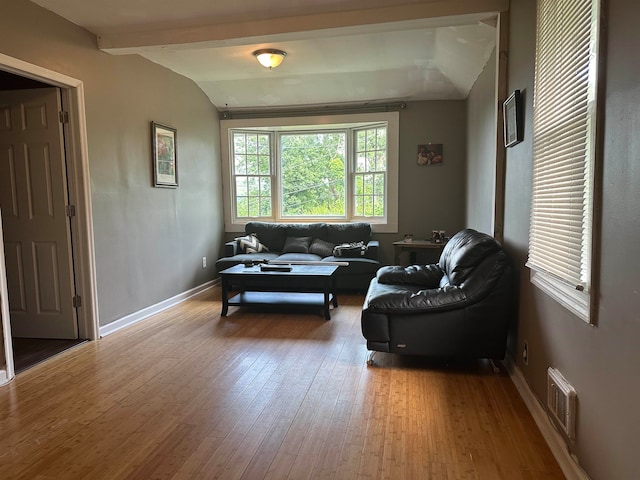 living room with hardwood / wood-style flooring and vaulted ceiling with beams