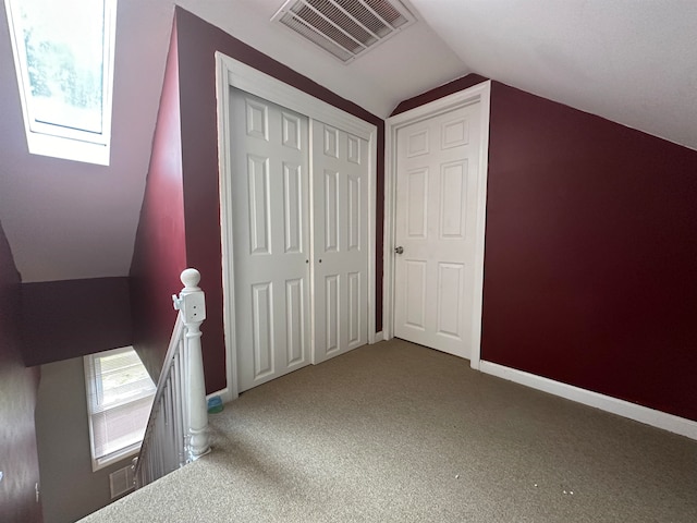 additional living space with lofted ceiling with skylight and carpet flooring