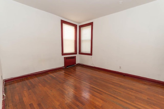 empty room with dark hardwood / wood-style floors and radiator heating unit