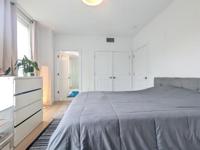 bedroom with a closet, visible vents, and light wood-style floors