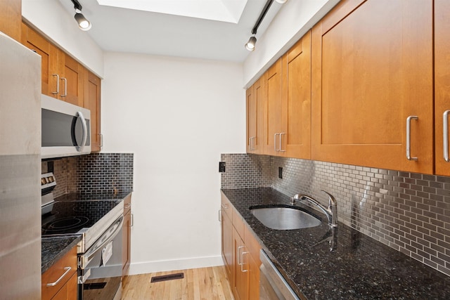 227 Bay St Unit 4B, Jersey City, NJ 07302 - kitchen featuring appliances with stainless steel finishes, tasteful backsplash, dark stone counters, and light wood-type flooring