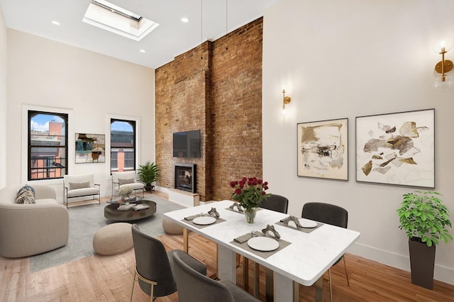 227 Bay St Unit 4B, Jersey City, NJ 07302 - dining area featuring a high ceiling, a skylight, wood finished floors, a large fireplace, and brick wall
