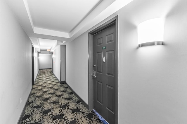 corridor with baseboards and dark floors