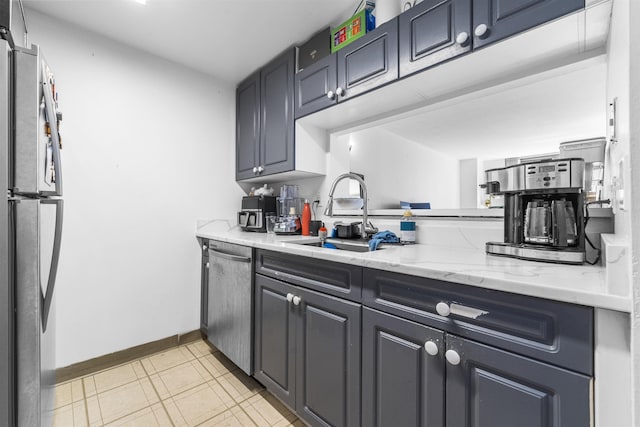 kitchen with baseboards, a sink, appliances with stainless steel finishes, and light stone counters