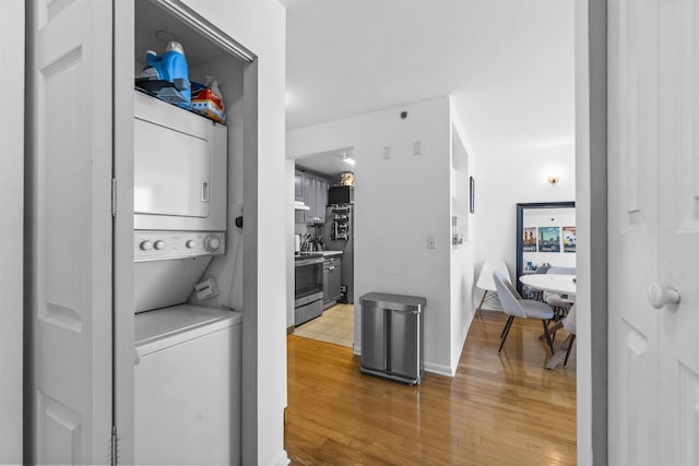 laundry room with laundry area, stacked washing maching and dryer, and light wood-style flooring