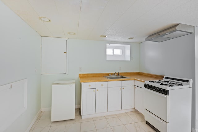 64 W 57th St, Bayonne, NJ 07002 - kitchen with white range with gas cooktop, wall chimney exhaust hood, light countertops, fridge, and recessed lighting