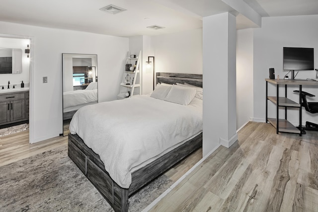bedroom featuring baseboards, visible vents, a sink, and light wood-style flooring