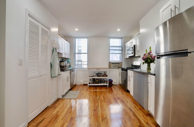 kitchen with appliances with stainless steel finishes, light hardwood / wood-style flooring, white cabinetry, and a wall mounted AC