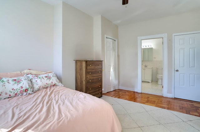 bedroom with connected bathroom and light parquet floors