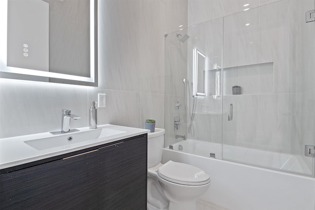 full bathroom featuring toilet, vanity, tile walls, and enclosed tub / shower combo