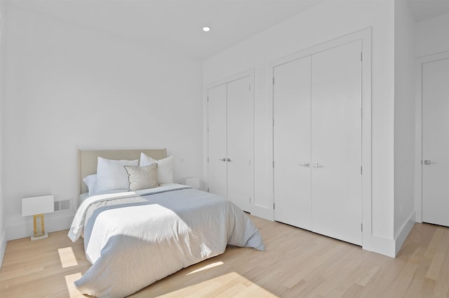 bedroom featuring multiple closets and light wood-type flooring