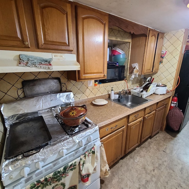 kitchen featuring gas range, tasteful backsplash, and sink