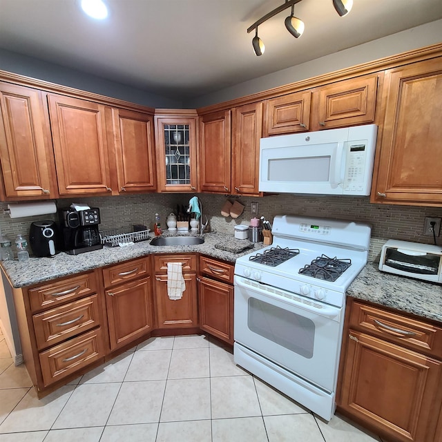 kitchen featuring sink, tasteful backsplash, light stone counters, white appliances, and light tile patterned floors