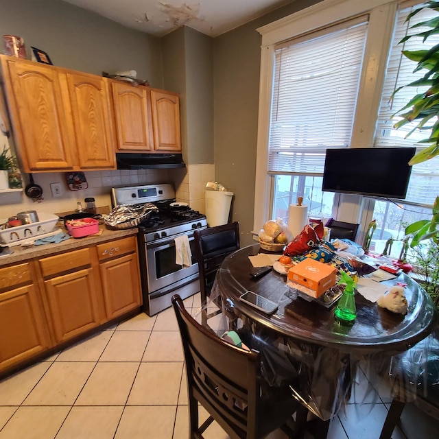 kitchen featuring backsplash, stainless steel gas range oven, and light tile patterned floors