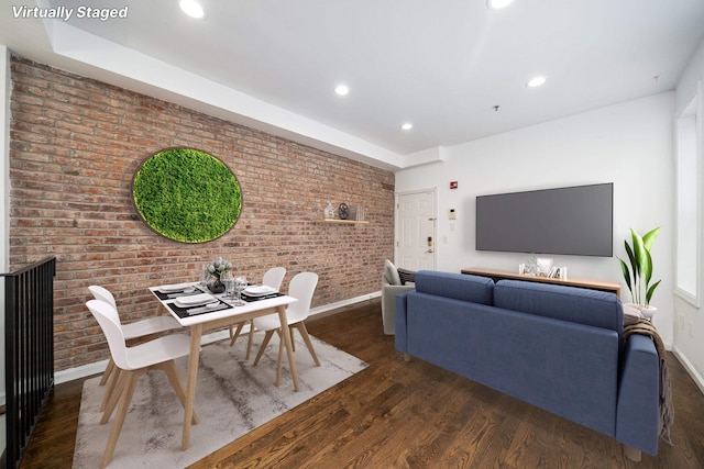 living room with dark hardwood / wood-style floors and brick wall