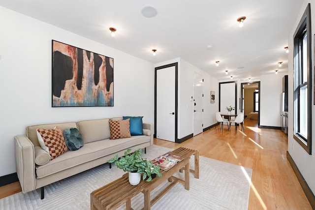 living area featuring light wood-style flooring and baseboards