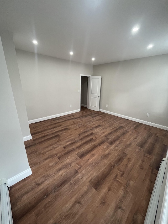 spare room featuring recessed lighting, dark wood finished floors, and baseboards