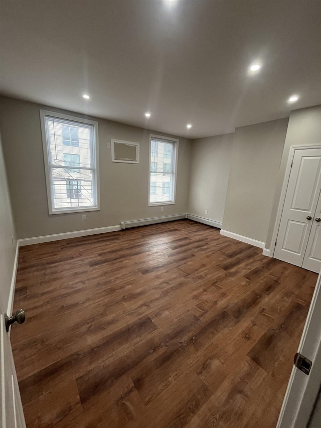 empty room with baseboards, dark wood-type flooring, and recessed lighting