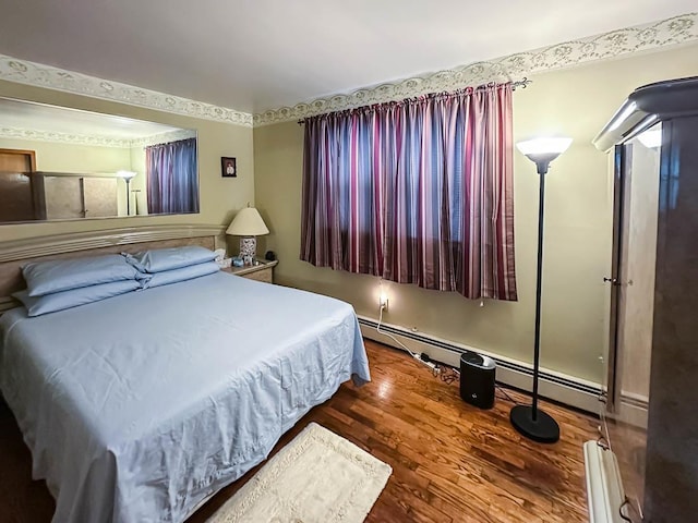 bedroom featuring baseboard heating and wood finished floors
