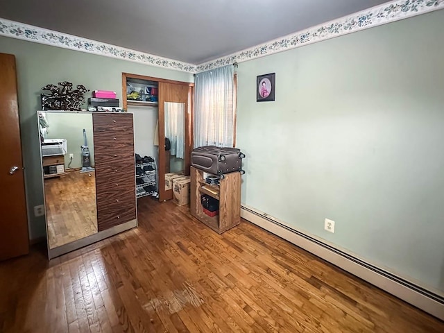 interior space featuring a baseboard heating unit and hardwood / wood-style floors