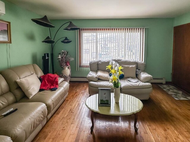 living area with a wall unit AC, wood-type flooring, and baseboard heating
