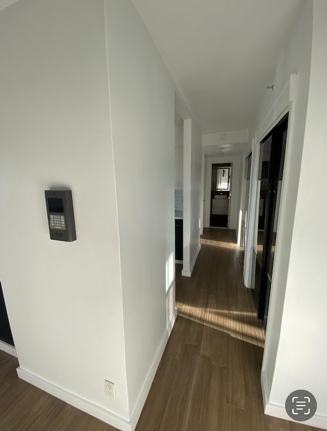 hallway featuring baseboards and dark wood-type flooring