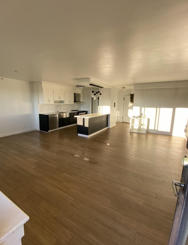 unfurnished living room featuring a sink, baseboards, and dark wood finished floors