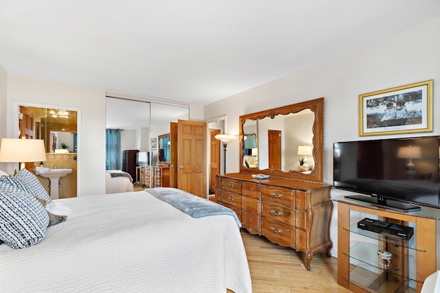 bedroom with light hardwood / wood-style floors, a closet, and ensuite bath