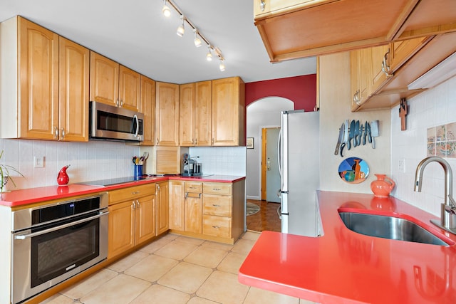 kitchen with tasteful backsplash, sink, light tile patterned flooring, and appliances with stainless steel finishes