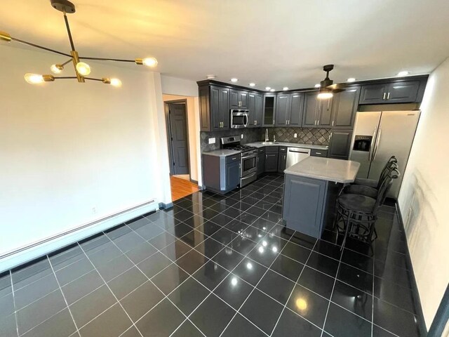 119 W 19th St, Bayonne, NJ 07002 - kitchen with appliances with stainless steel finishes, decorative backsplash, dark tile patterned floors, ceiling fan, and light countertops