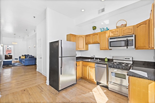 231 Grand St Unit 5R, Hoboken, NJ 07030 - kitchen featuring appliances with stainless steel finishes, a sink, light wood-style floors, dark stone countertops, and open floor plan