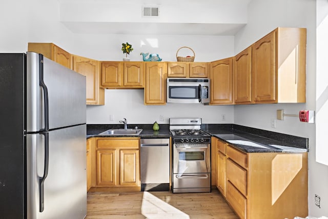 231 Grand St Unit 5R, Hoboken, NJ 07030 - kitchen featuring appliances with stainless steel finishes, a sink, light wood-style flooring, and dark stone counters