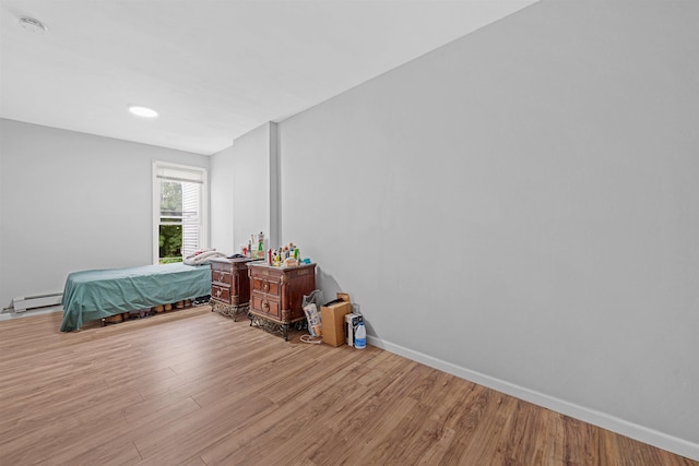 bedroom with baseboard heating and light hardwood / wood-style floors