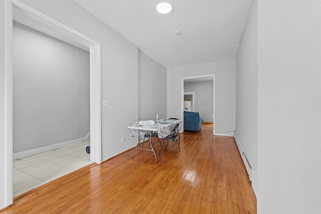 hallway featuring baseboard heating and light hardwood / wood-style flooring