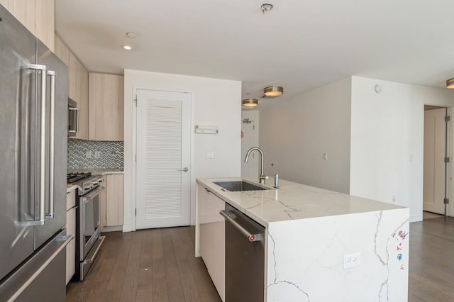 kitchen featuring dark wood finished floors, an island with sink, modern cabinets, high quality appliances, and a sink