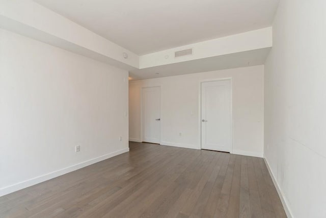 unfurnished room featuring wood finished floors, visible vents, and baseboards