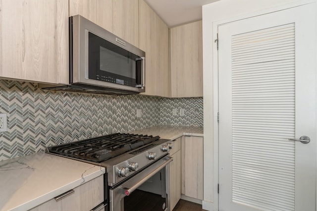 kitchen featuring modern cabinets, appliances with stainless steel finishes, decorative backsplash, and light brown cabinetry