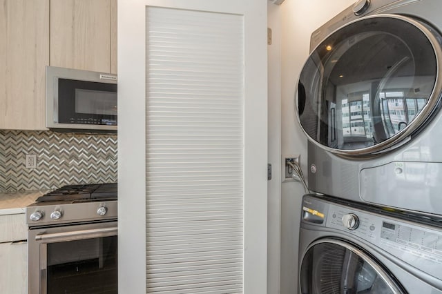 clothes washing area featuring stacked washer / dryer and laundry area